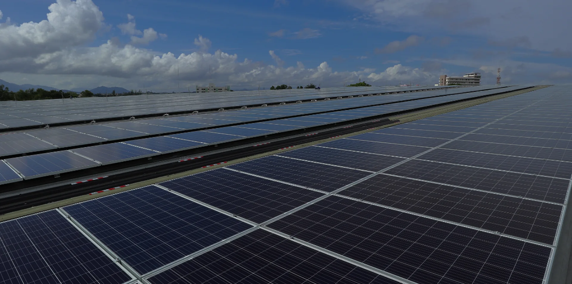 Großes Feld mit Solarpanelen unter bewölktem Himmel und blauem Himmel im Hintergrund