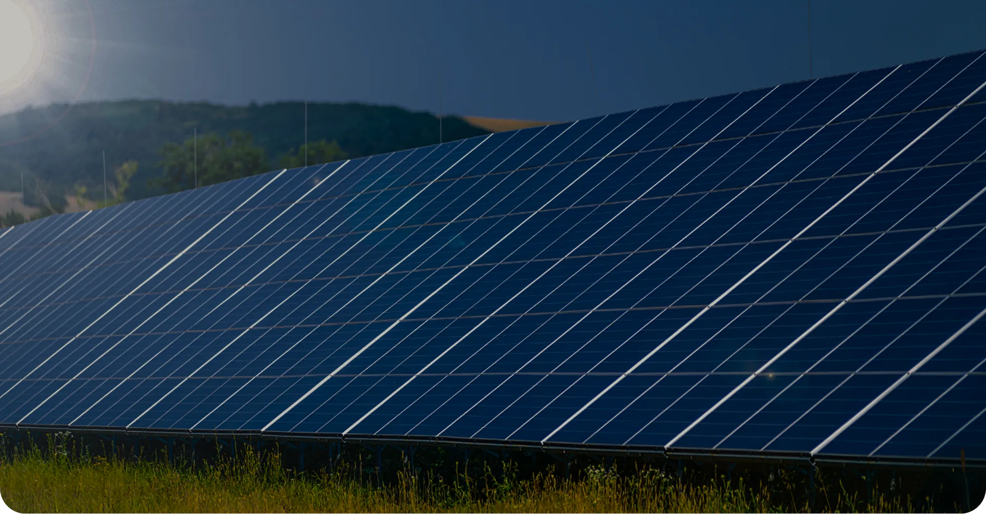 Solaranlage mit großen blauen Photovoltaikmodulen auf einer Wiese bei Sonnenlicht.