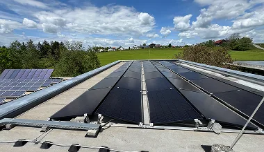 Dach mit Solarpaneelen unter bewölktem Himmel und grüner Landschaft im Hintergrund zur Erstellung eines Wertgutachtens