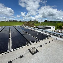Flachdach mit Solarmodulen und betoniertem Halter gegen Wind bei sonnigem Himmel mit Wolken, Begehung einer Anlage zur Erstellung eines Wertgutachtens